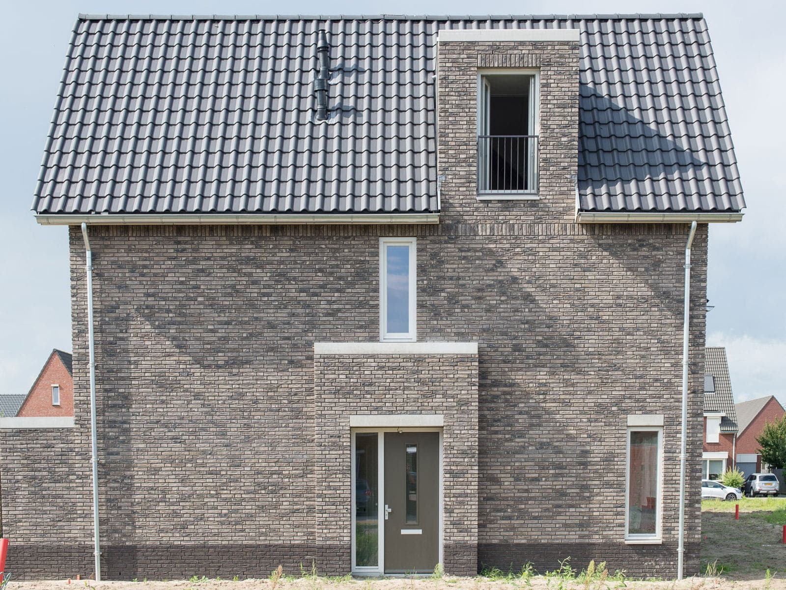 zijaanzicht van een grijsbruin huis met dakpannen