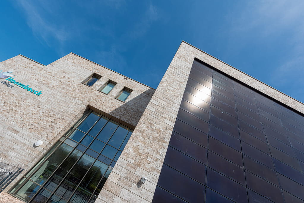 Licht gebouw met zwarte vlakken tegen een blauwe lucht van onderen gefotografeerd