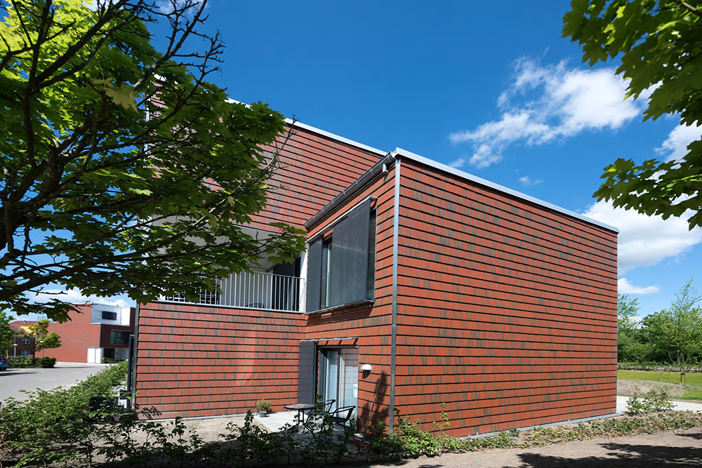 Zijaanzicht van een roodbruin gebouw met Architile tegels