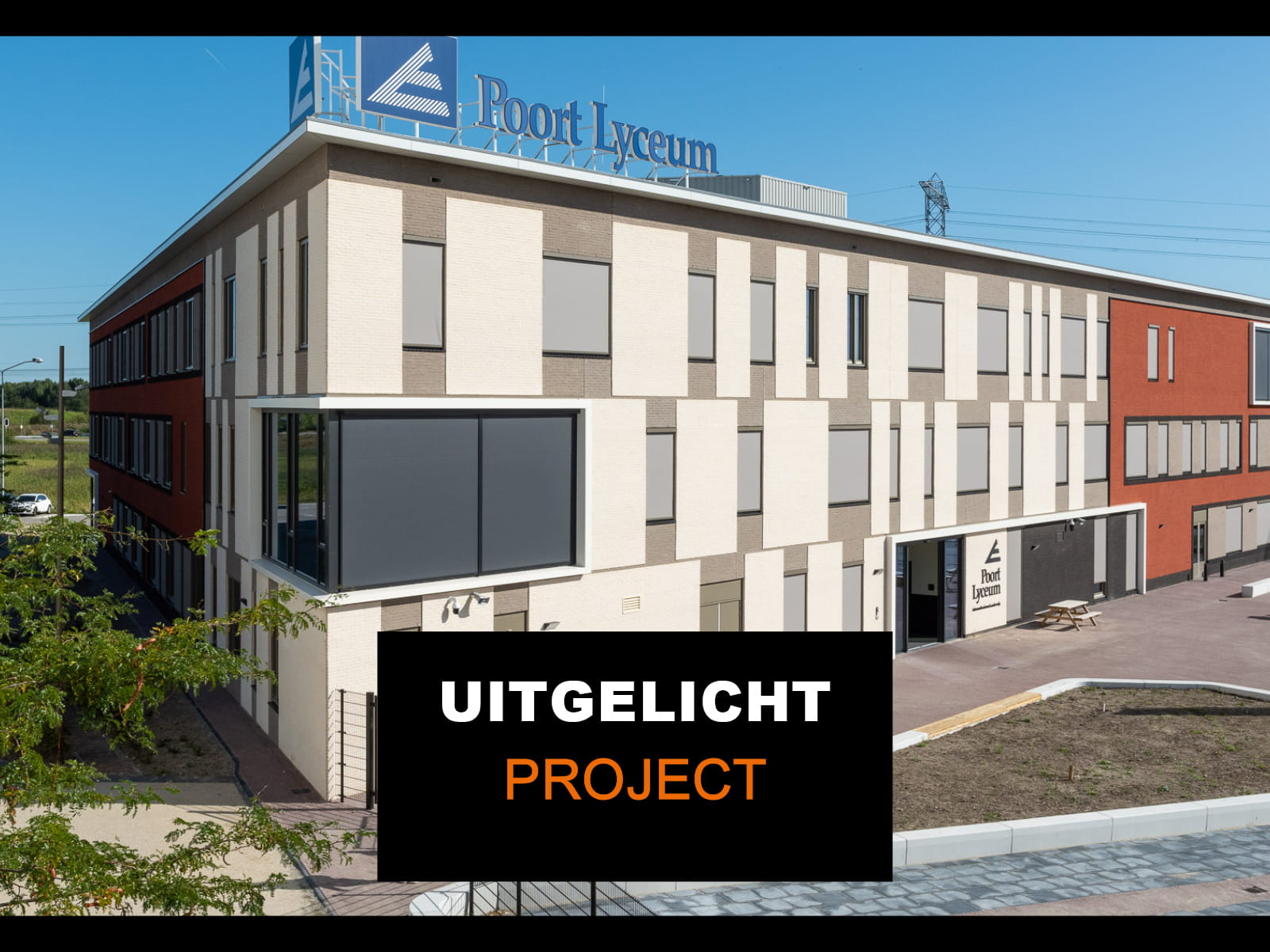 Poort Lyceum in Almere vanaf hoogte bekeken. Vanaf de hoek met witte vlakken, aan de rechterkant rode vlakken. Met schoolplein op de voorgrond.