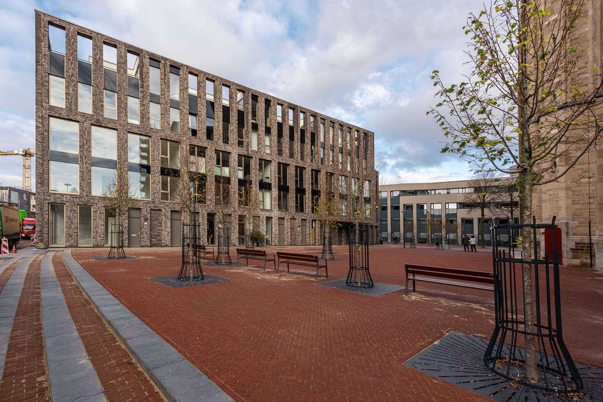 Zijkant van lichte gevel met grote ramen en plein op de voorgrond