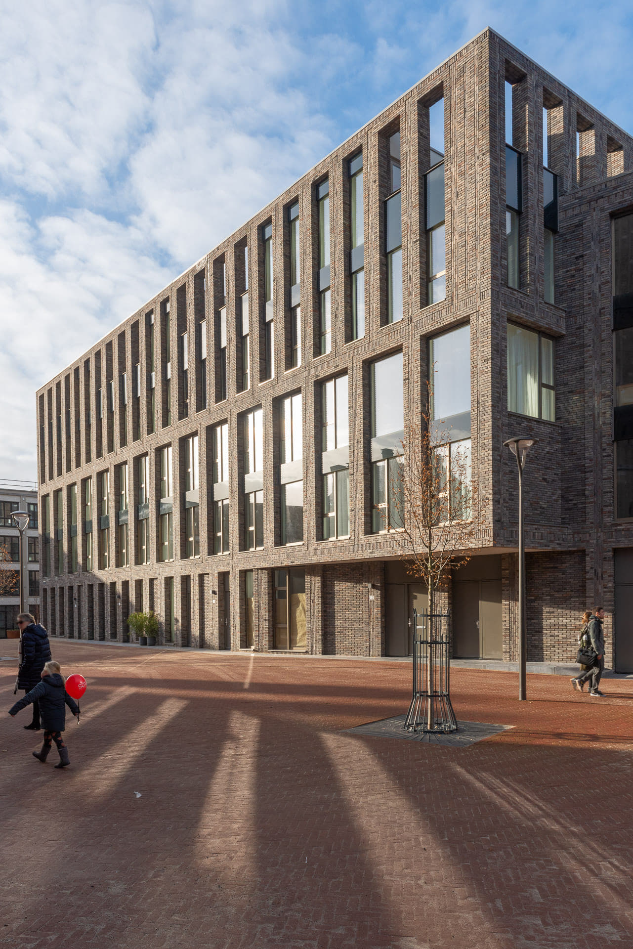 zijaanzicht van een grote partij ramen en lijnen in de gevel met op de voorgrond een plein