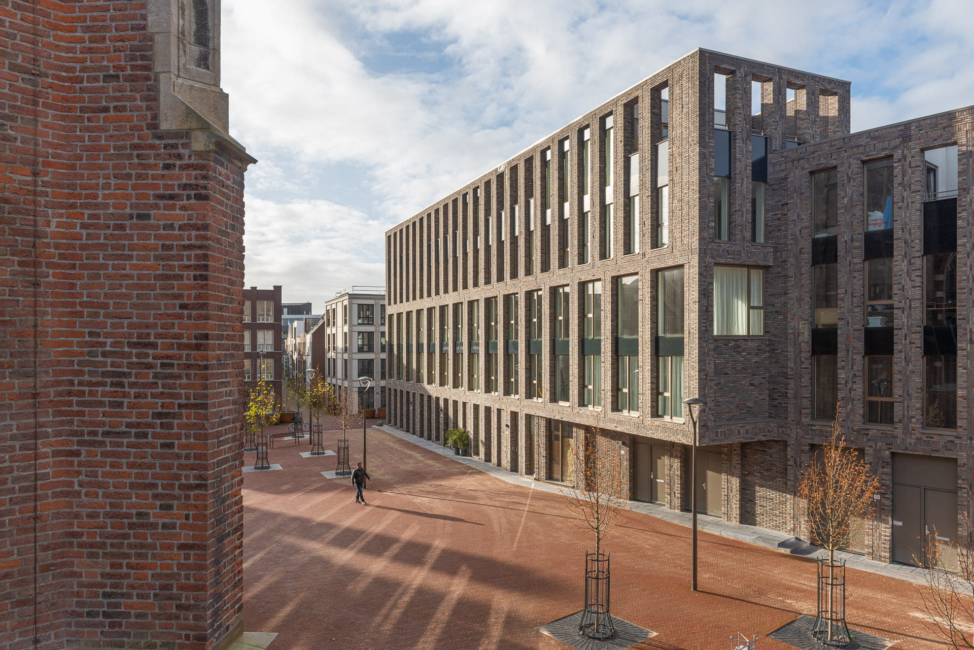 zijaanzicht van een grote partij ramen en lijnen in de gevel met op de voorgrond een plein