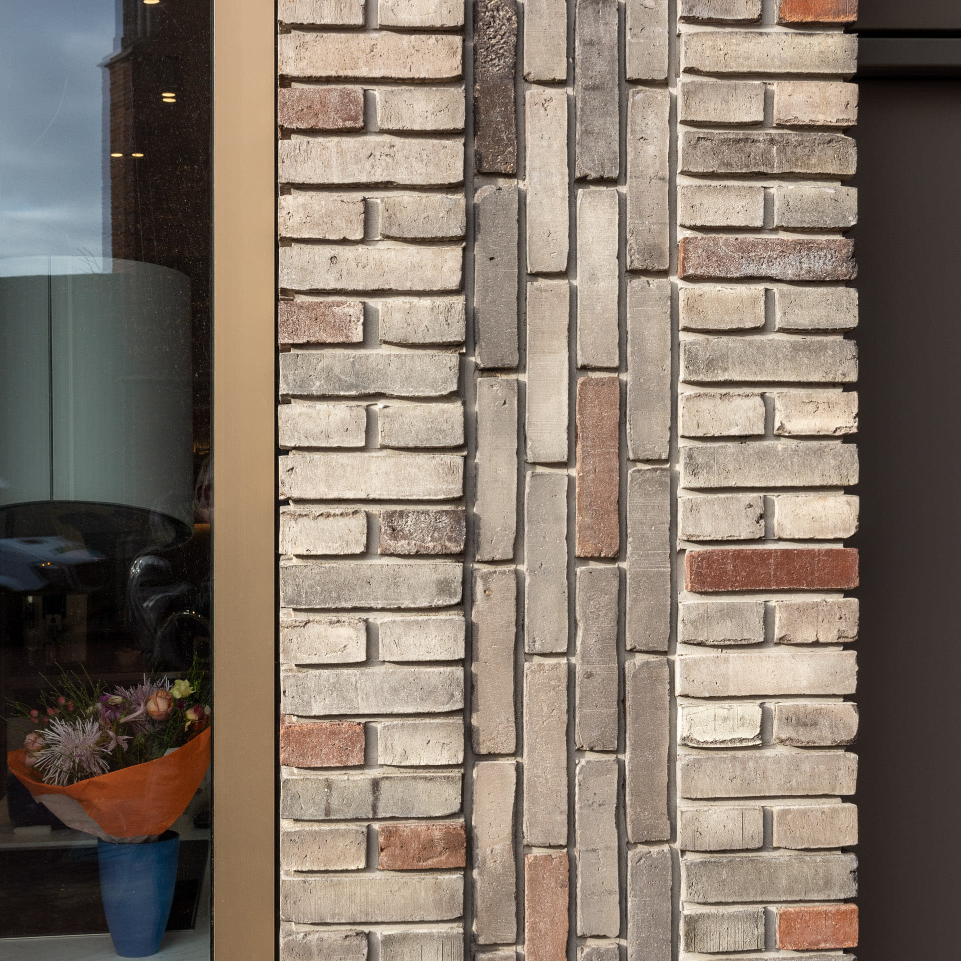 Detail van een lichte gevel met staand en terugliggend metselwerk in prefab