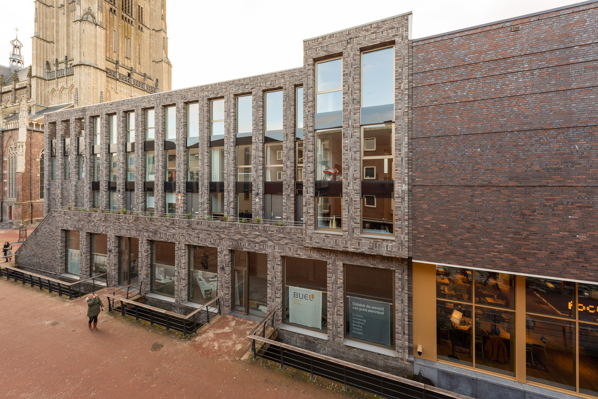 een rij van de gevel van een bioscoop, woongebouw en een oude kerk op de achtergrond