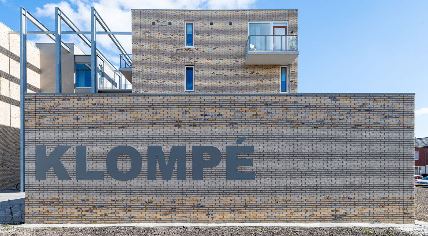 Muur met gele gevelstenen en de aan Klompé erop